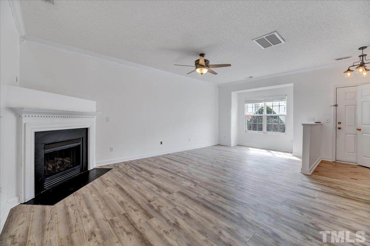 3367 Bridgeville Road Raleigh, NC 27610 - Photo 7 of 34 a view of empty room with a fireplace and wooden floor