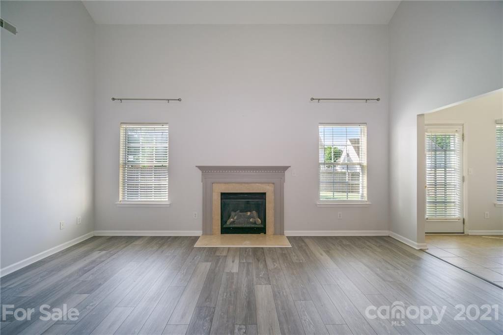 141 Rhyne Springs Road Mount Holly, NC 28120 - Photo 3 of 17 an empty room with wooden floor fireplace and windows