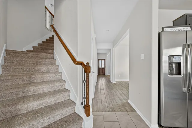 a view of a hallway with staircase and white kitchen