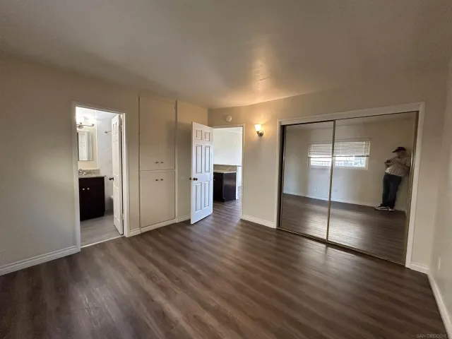 a view of an empty room and wooden floor and a kitchen