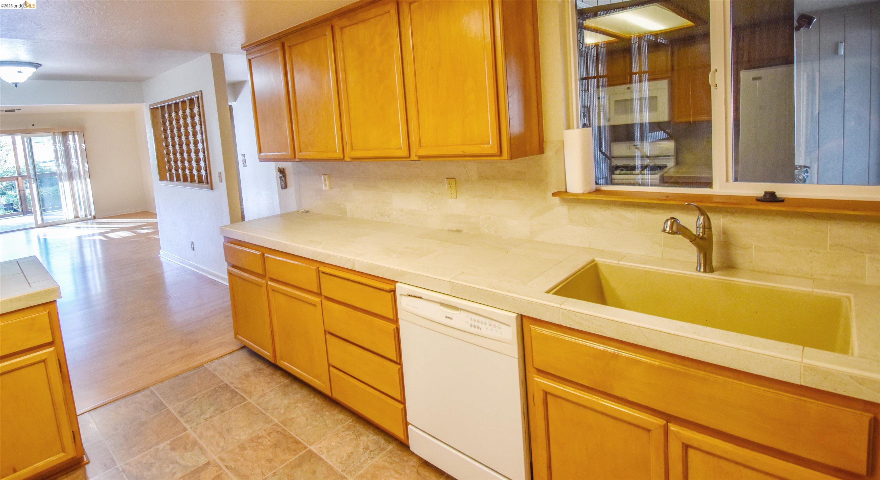23685 Marble Quarry Road, Unit 22 Columbia, CA 95310 - Photo 11 of 33 Kitchen featuring white dishwasher, tile countertops, backsplash, wood finish cabinetry, and stone finish floors