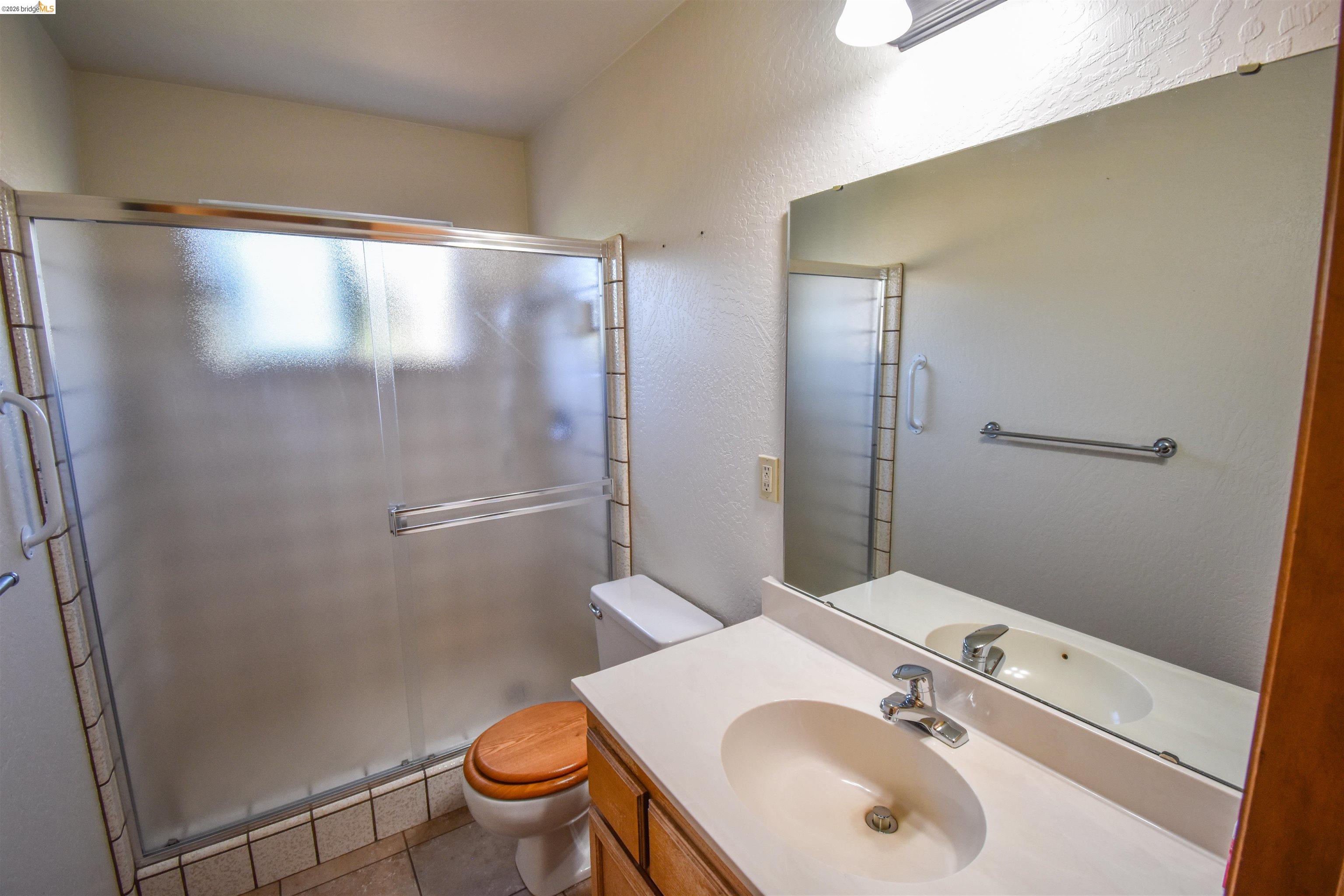 23685 Marble Quarry Road, Unit 22 Columbia, CA 95310 - Photo 16 of 33 Full bathroom featuring a textured wall, vanity, a shower stall, and light tile patterned floors