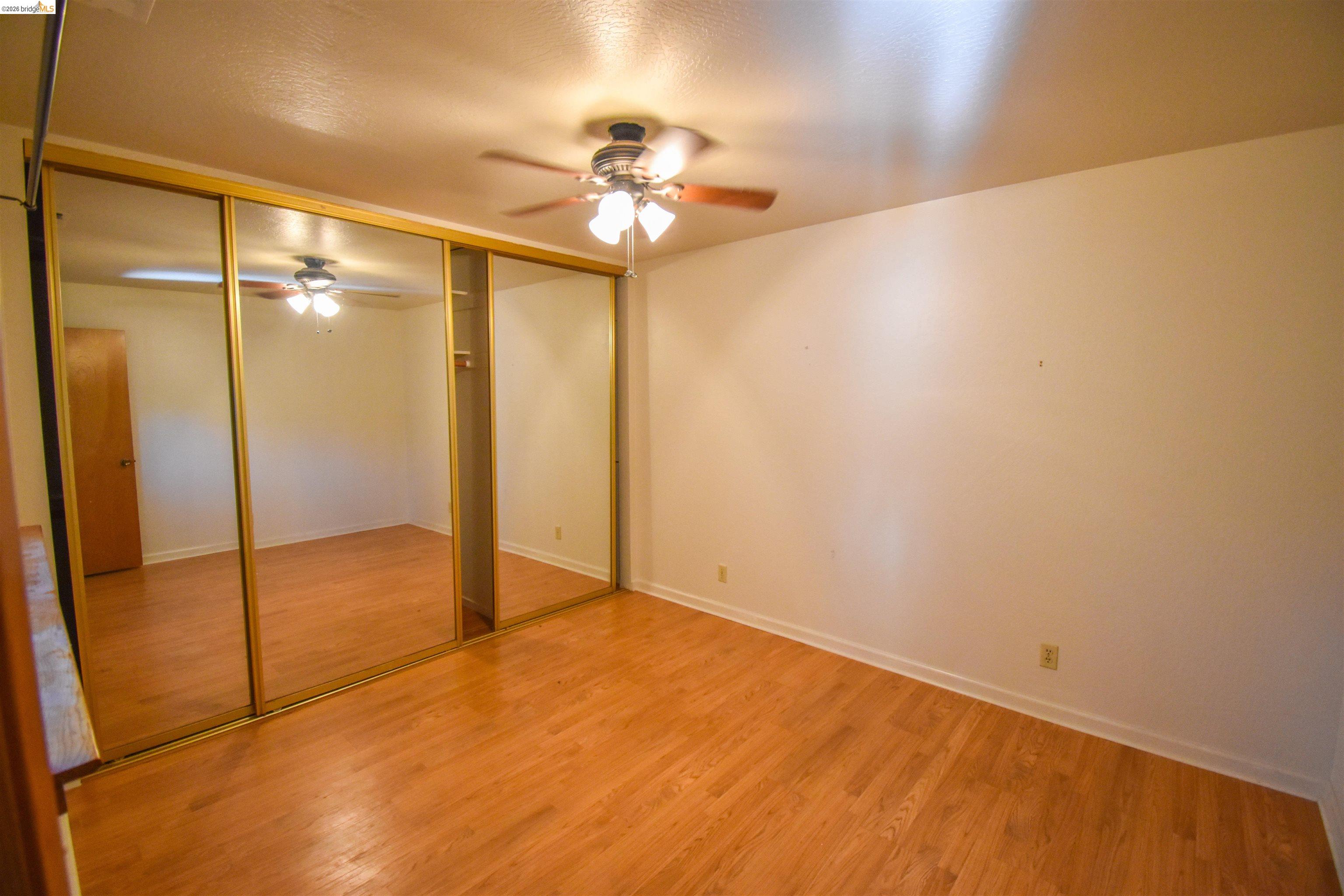 23685 Marble Quarry Road, Unit 22 Columbia, CA 95310 - Photo 17 of 33 Unfurnished bedroom featuring wood finished floors, a ceiling fan, and a closet