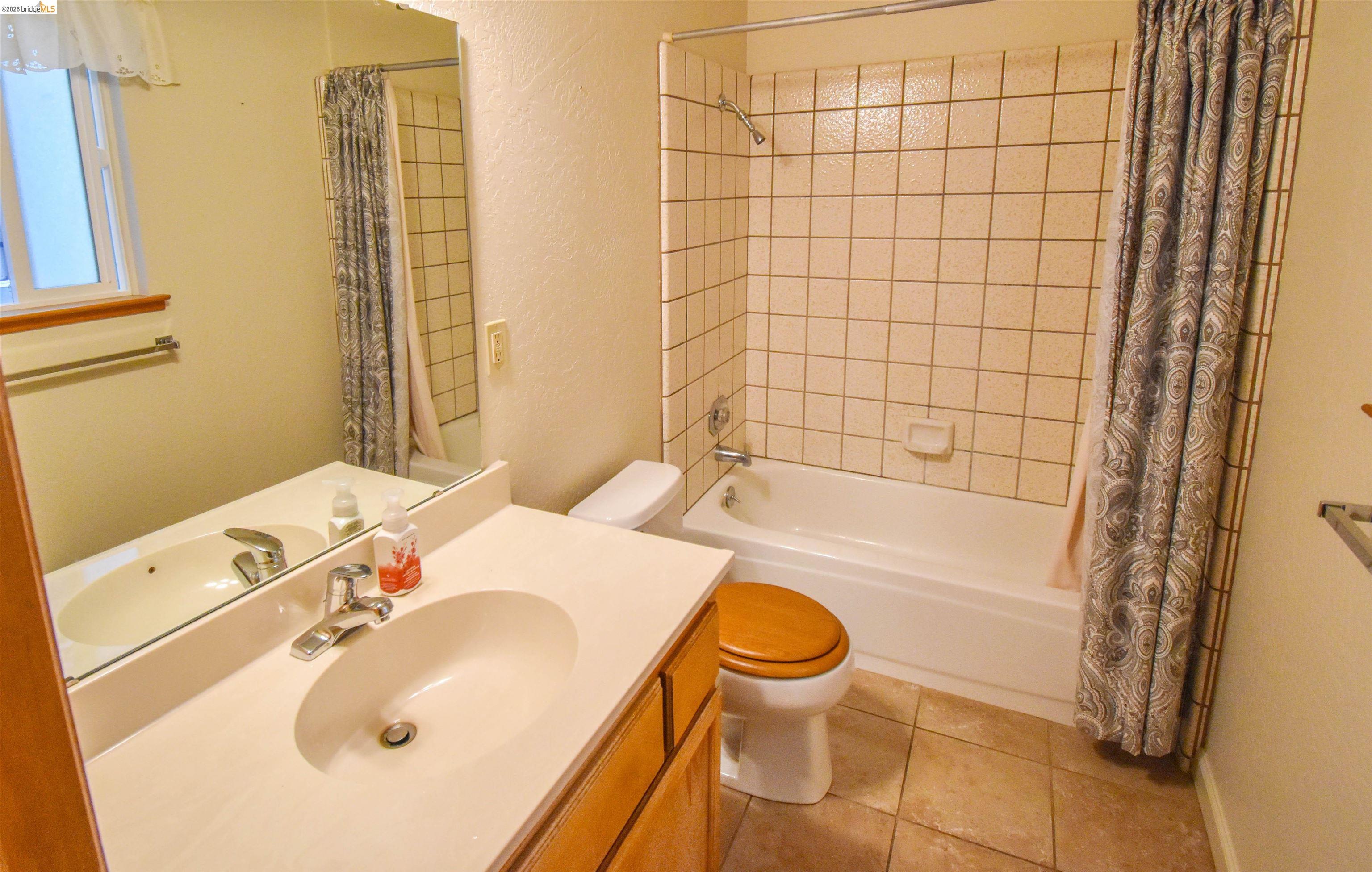 23685 Marble Quarry Road, Unit 22 Columbia, CA 95310 - Photo 19 of 33 Bathroom featuring vanity, a textured wall, shower / tub combo with curtain, and light tile patterned flooring