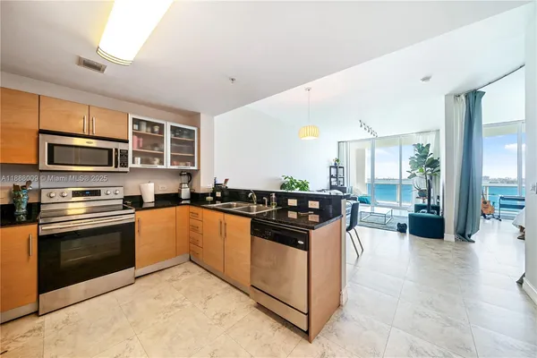 a kitchen with stainless steel appliances granite countertop a stove top oven a sink dishwasher a dining table and chairs with wooden floor