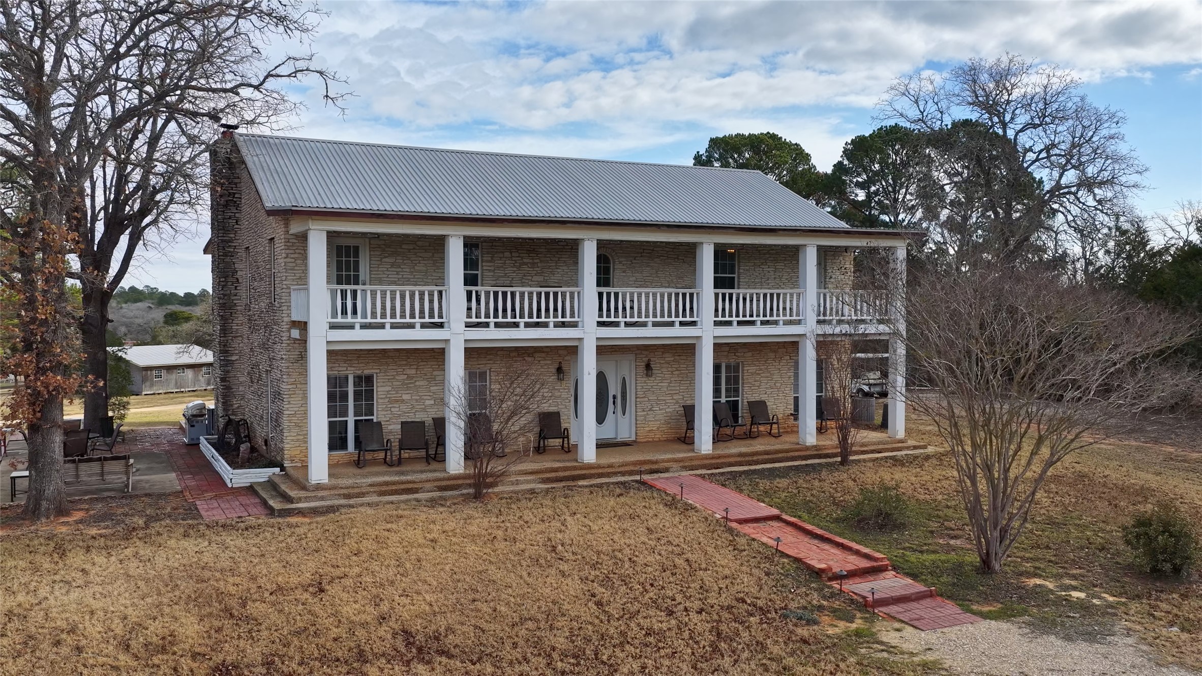 View of front of property with a metal roof, a front yard, and brick siding