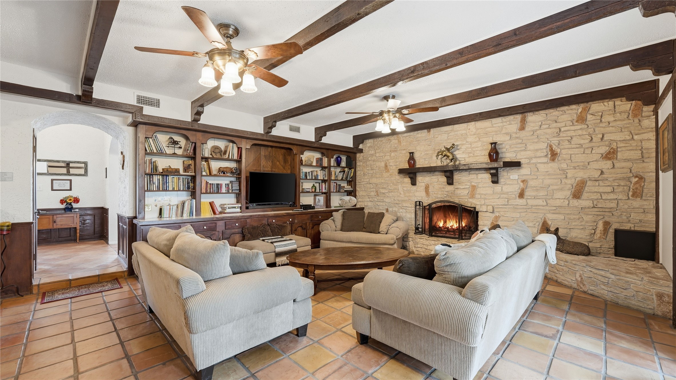 182 Little Ranch Road Red Rock, TX 78662 - Photo 18 of 40 Living area with a fireplace, beam ceiling, a ceiling fan, and arched walkways