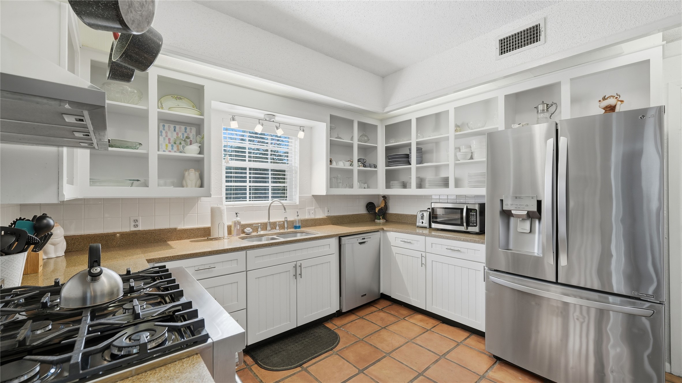 182 Little Ranch Road Red Rock, TX 78662 - Photo 21 of 40 Kitchen featuring stainless steel appliances, white cabinetry, open shelves, light tile patterned flooring, and tasteful backsplash