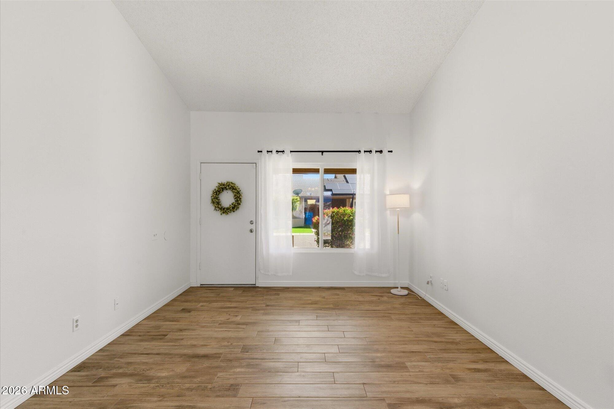 4208 East Carson Road Phoenix, AZ 85042 - Photo 3 of 25 a view of empty room with window and wooden floor