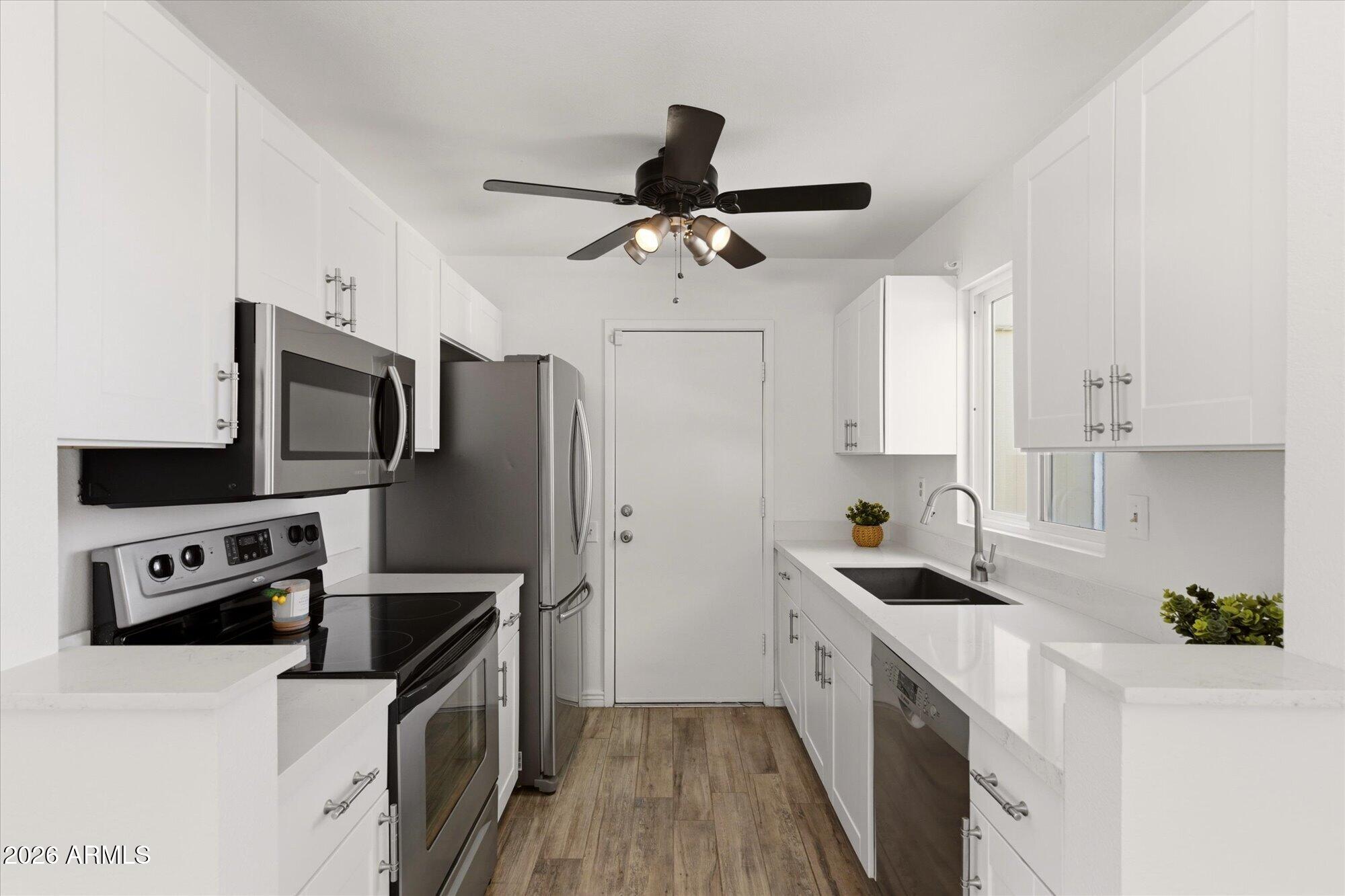4208 East Carson Road Phoenix, AZ 85042 - Photo 9 of 25 a kitchen with stainless steel appliances a stove a sink a refrigerator white cabinets and wooden floor