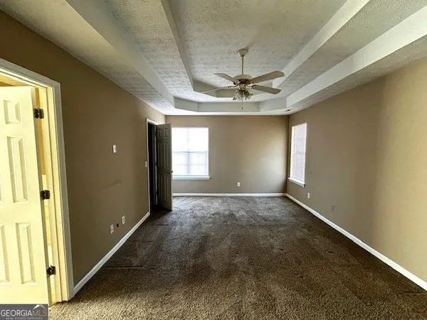 en empty room with windows and ceiling fan