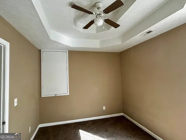 an empty room with a ceiling fan and carpet