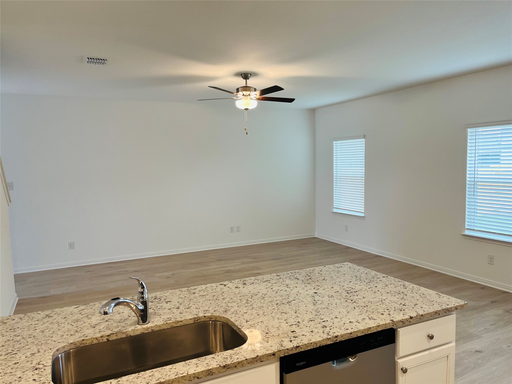 409 Silent Meadow Run Maxwell, TX 78656 - Photo 3 of 10 Kitchen featuring light stone countertops, dishwasher, light wood-style floors, white cabinetry, and a ceiling fan