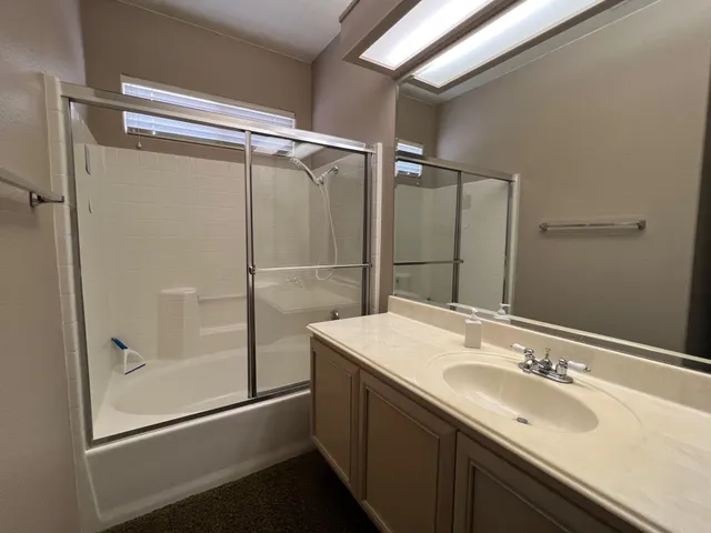 a bathroom with a sink mirror and shower