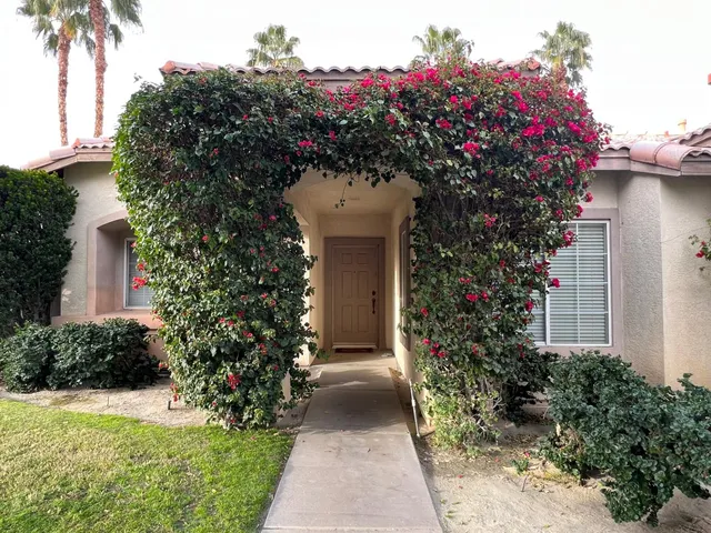 a front view of a house with a yard and potted plants