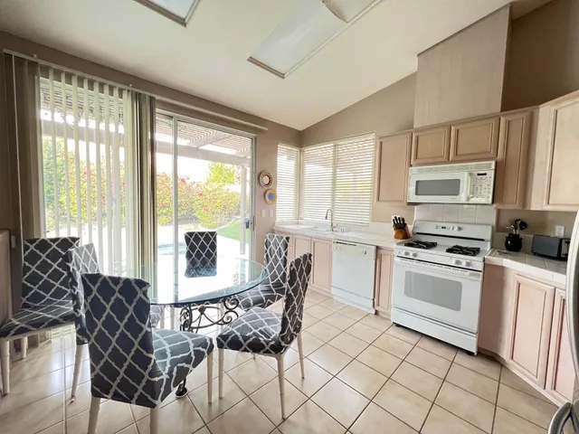 a kitchen with stainless steel appliances granite countertop a stove a refrigerator a sink dishwasher a dining table and chairs with wooden floor