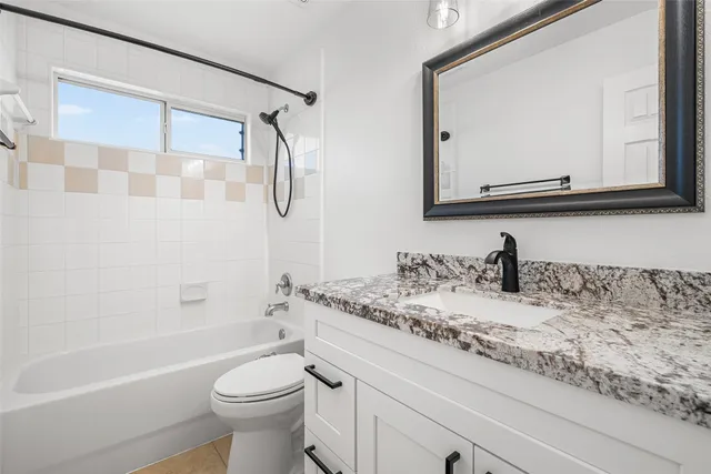 a bathroom with a granite countertop sink mirror vanity and toilet