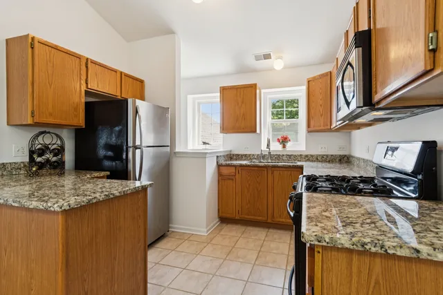a kitchen with stainless steel appliances granite countertop a stove a sink and a refrigerator