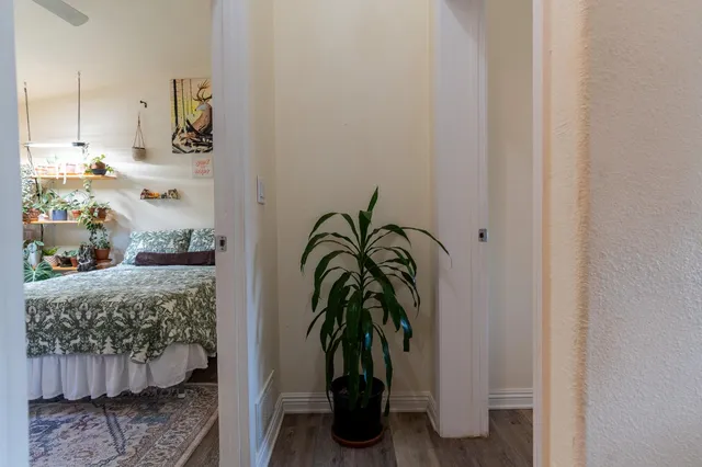 a bedroom with a bed table flowerpot and window