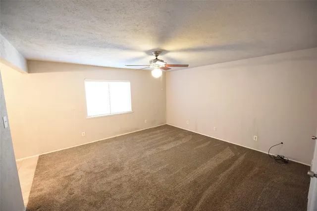 an empty room with a chandelier fan and windows