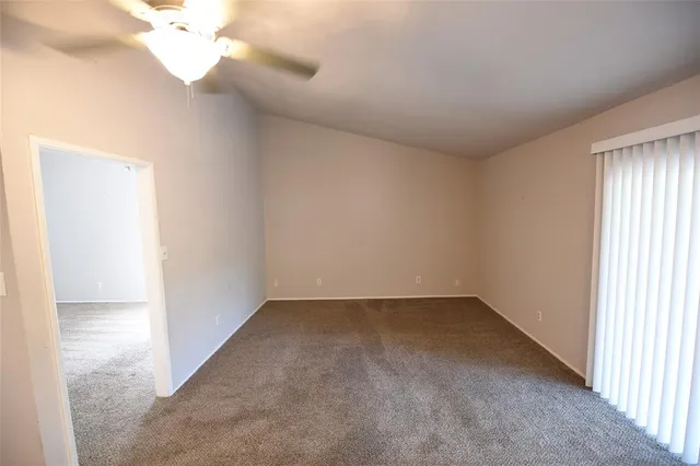 an empty room with a chandelier fan and windows