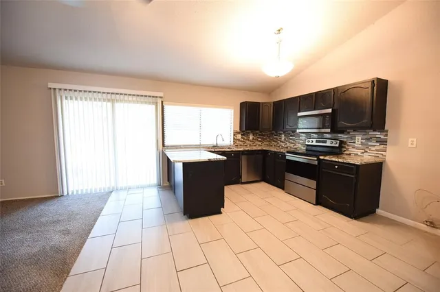 a kitchen with stainless steel appliances granite countertop a stove top oven a sink dishwasher and a refrigerator