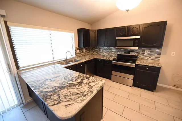 a kitchen with stainless steel appliances kitchen island granite countertop a sink stove and microwave