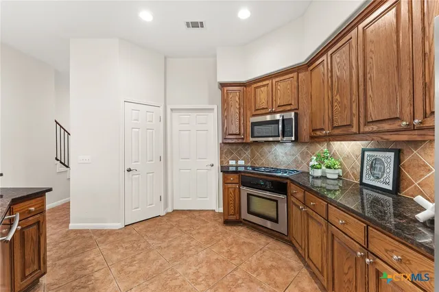 a kitchen with stainless steel appliances granite countertop a refrigerator and a stove