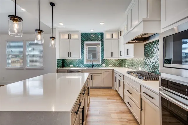 a large white kitchen with kitchen island a stove a sink a counter space and wooden floor
