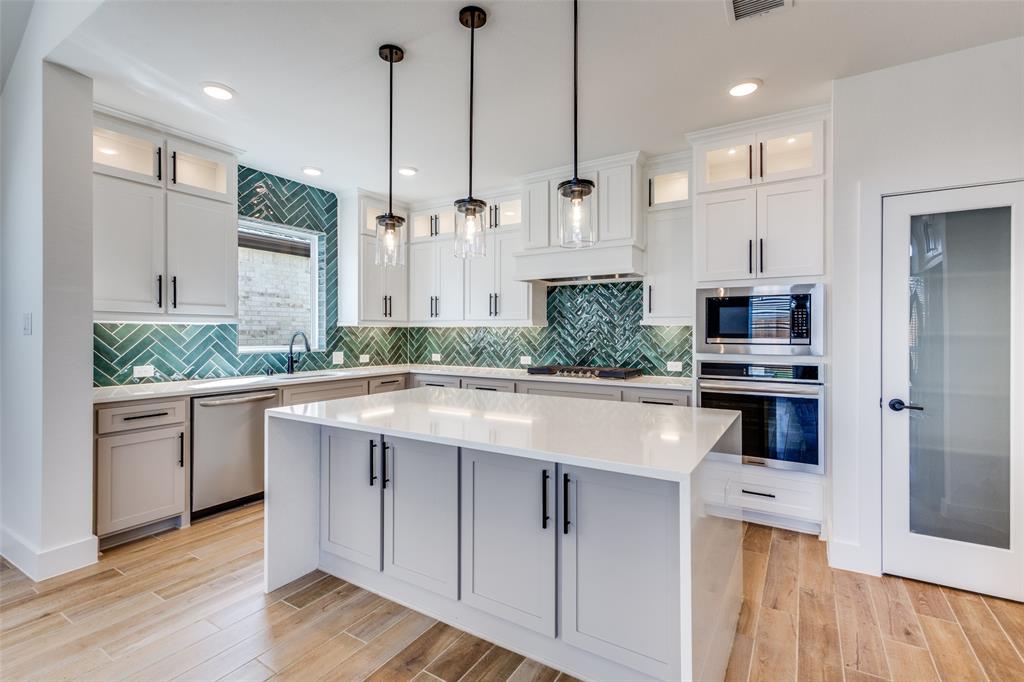 3308 Lakestriker Road Pilot Point, TX 76258 - Photo 12 of 25 a kitchen with kitchen island granite countertop a stove a sink and a refrigerator with wooden floor