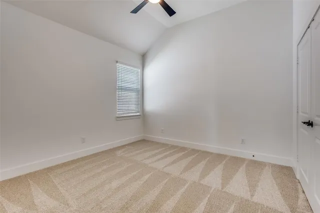 an empty room with chandelier fan and windows