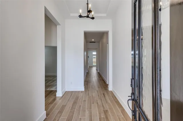 a view of a hallway with wooden floor and a bathroom