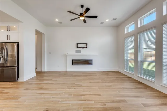 a view of a livingroom with a ceiling fan a fireplace and a large window