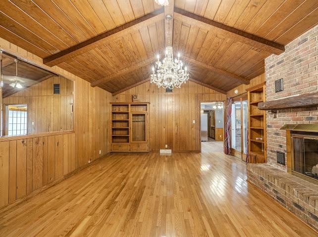 660 Hinton Road Counce, TN 38326 - Photo 10 of 40 Vaulted wood-paneled ceiling with exposed beams, wood-finish flooring, brick fireplace with mantel, crystal chandelier, and built-in shelving
