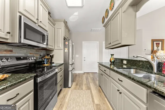 a kitchen with stainless steel appliances granite countertop a stove a sink and a microwave