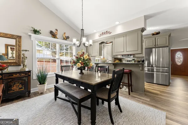 a kitchen with stainless steel appliances a dining table chairs stove refrigerator and cabinets