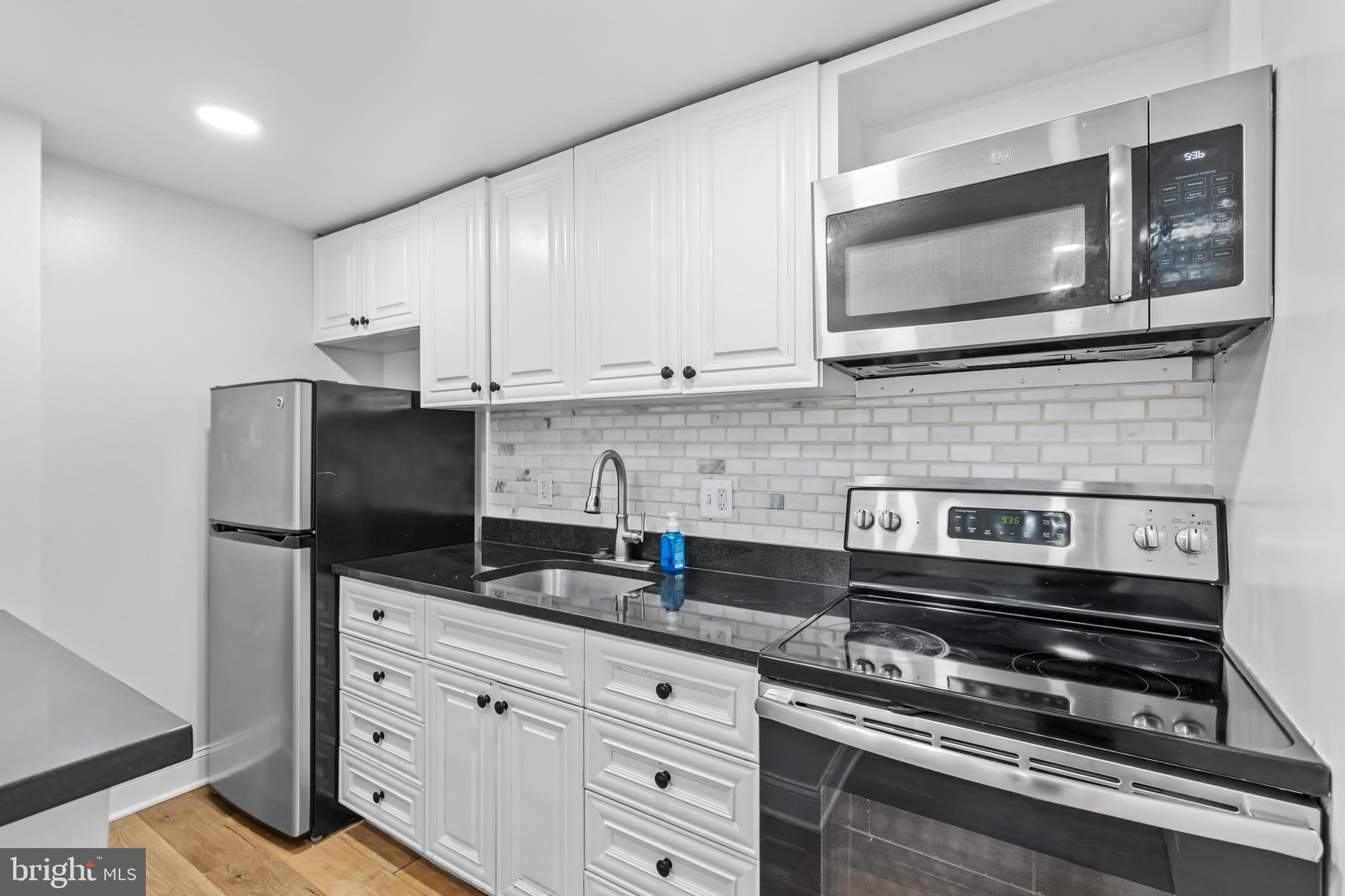 2032 15th Street Northwest, Unit 2 Washington, DC 20009 - Photo 11 of 28 a kitchen with granite countertop cabinets stainless steel appliances and wooden cabinets