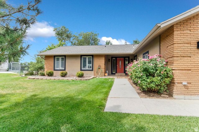 2863 Fallentine Road Sandy, UT 84093 - Photo 4 of 48 Exterior facade featuring a red entry door, brick and stucco finishes, and a concrete walkway