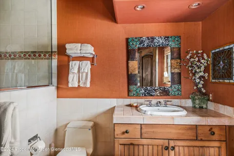 a bathroom with a sink and mirror with toilet