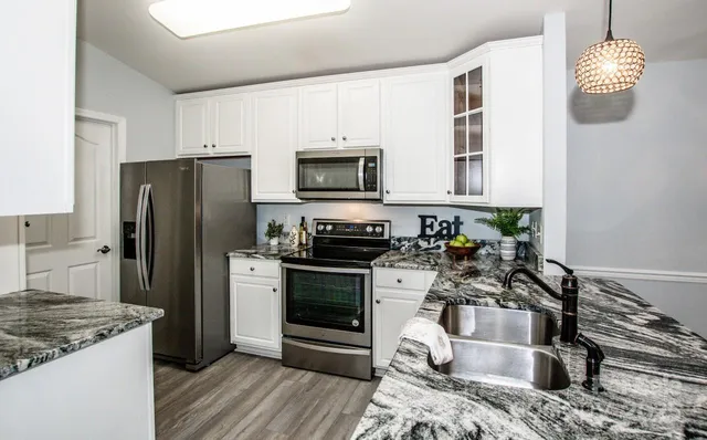 a kitchen with granite countertop a stove sink and refrigerator