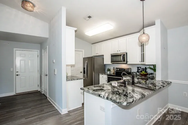 a kitchen with stainless steel appliances granite countertop a refrigerator a stove top oven a sink and dishwasher