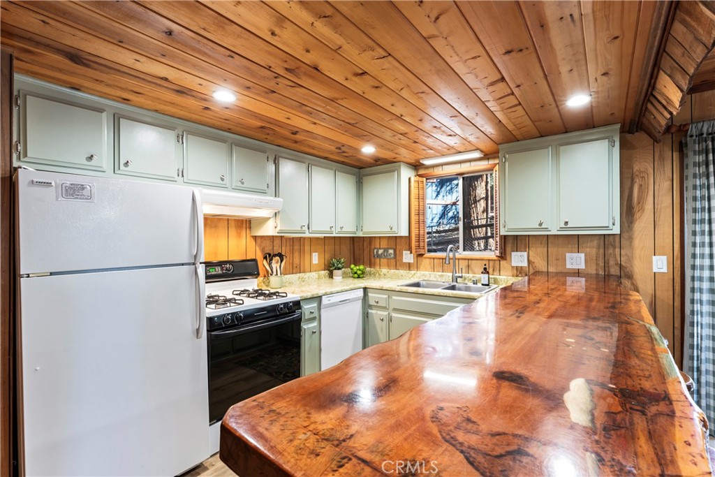 930 Bear Mountain Road Big Bear City, CA 92314 - Photo 16 of 39 a kitchen with stainless steel appliances granite countertop a refrigerator a sink dishwasher a stove and white countertops with wooden floor