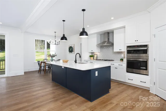 a kitchen with stainless steel appliances kitchen island a sink a stove a refrigerator and white cabinets