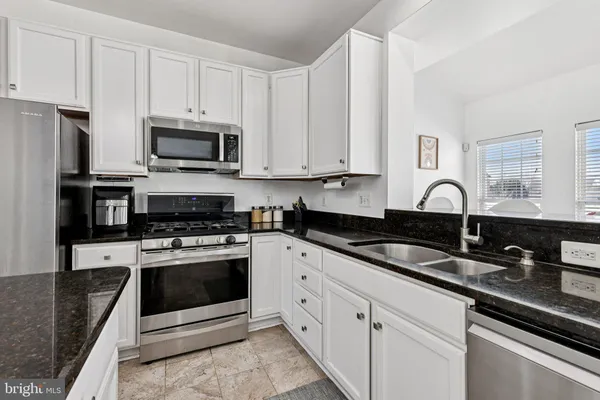 a kitchen with stainless steel appliances kitchen island granite countertop a sink and a stove
