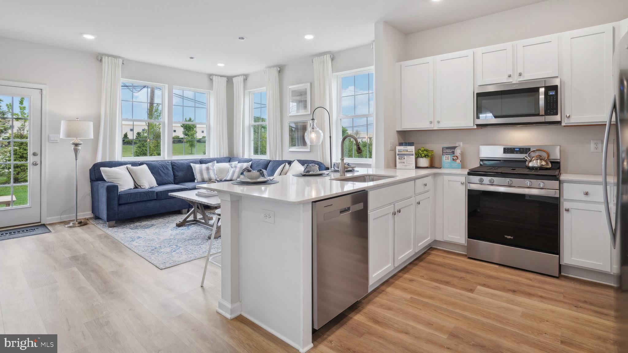 31 Alexander Way Westampton, NJ 08060 - Photo 4 of 14 a kitchen with stainless steel appliances granite countertop a stove top oven a sink dishwasher and white cabinets with wooden floor