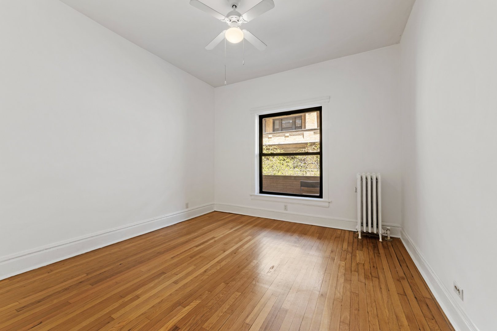 728 West Sheridan Road, Unit 2N Chicago, IL 60613 - Photo 11 of 18 an empty room with wooden floor chandelier fan and windows