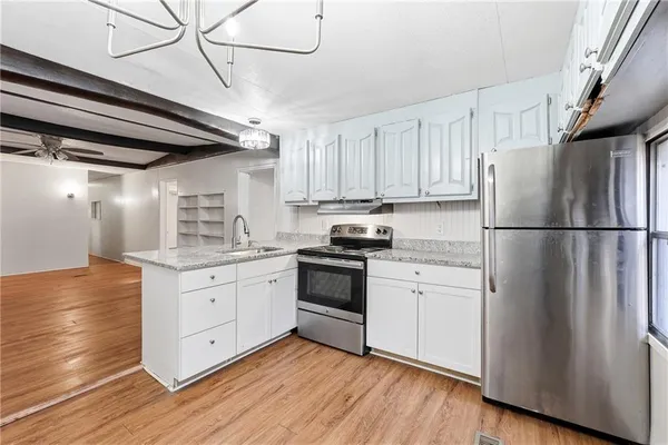 a kitchen with granite countertop stainless steel appliances a refrigerator a sink and cabinets