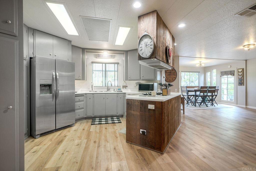18218 Paradise Mountain Road Valley Center, CA 92082 - Photo 7 of 42 a kitchen with stainless steel appliances kitchen island granite countertop a refrigerator a stove and a wooden floors