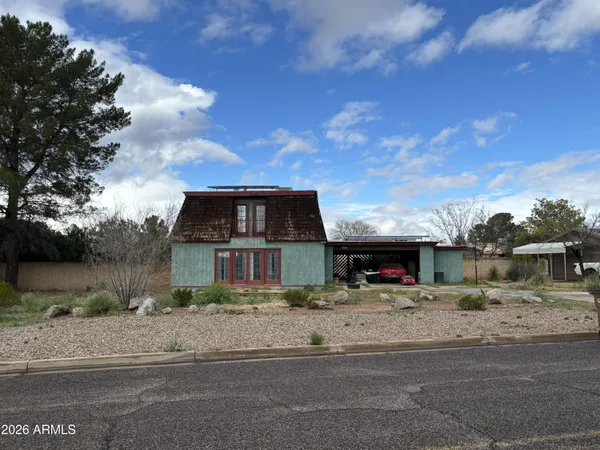 a front view of a house with a garden and trees
