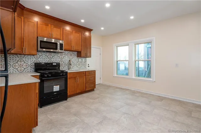 a kitchen with stainless steel appliances granite countertop a stove a sink and a microwave